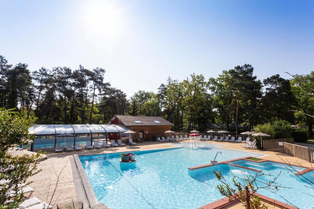 艾克塞恩维克斯Camping La Pinède的一座大型游泳池,其建筑背景为: