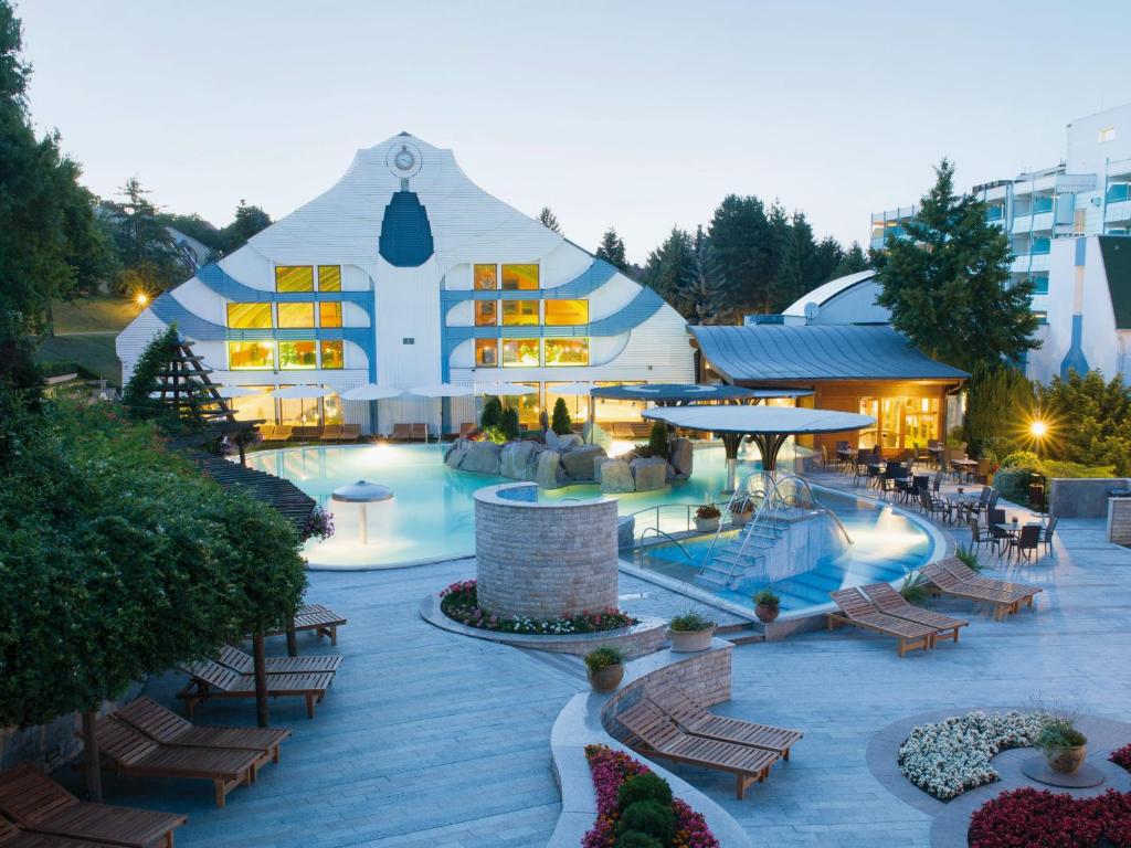 赫维兹Hotel Carbona Thermal Spa的一座白色的大建筑,设有游泳池和桌椅
