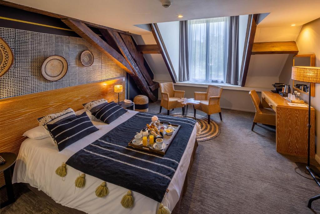 米尼亚卢博瓦尔Garrigae Manoir de Beauvoir Poitiers Sud - Hotel & Spa的一间酒店客房,配有一张床铺,上面放着一个食物托盘