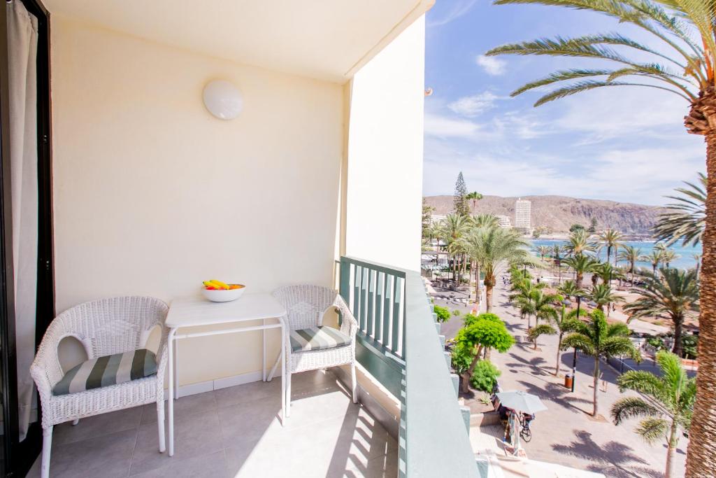 洛斯克里斯蒂亚诺斯Apartment Carmen Sunrise, Los Cristianos的享有海滩和棕榈树景致的阳台
