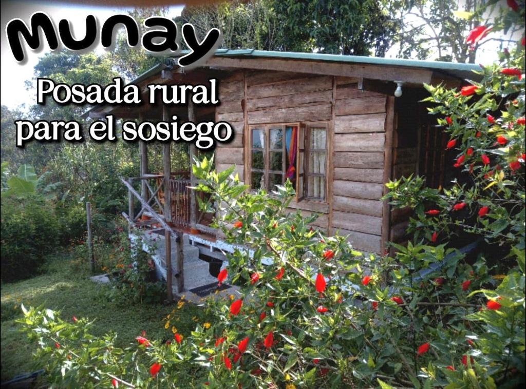 AlcaláMUNAY, Posada rural para el sosiego的一座带红花灌木的小木小屋