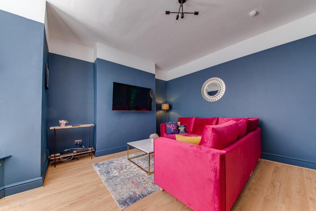 利物浦Air Host and Stay - Rockfield Lodge, sleep 12 free parking next to LFC的客厅设有粉红色的沙发和蓝色的墙壁。
