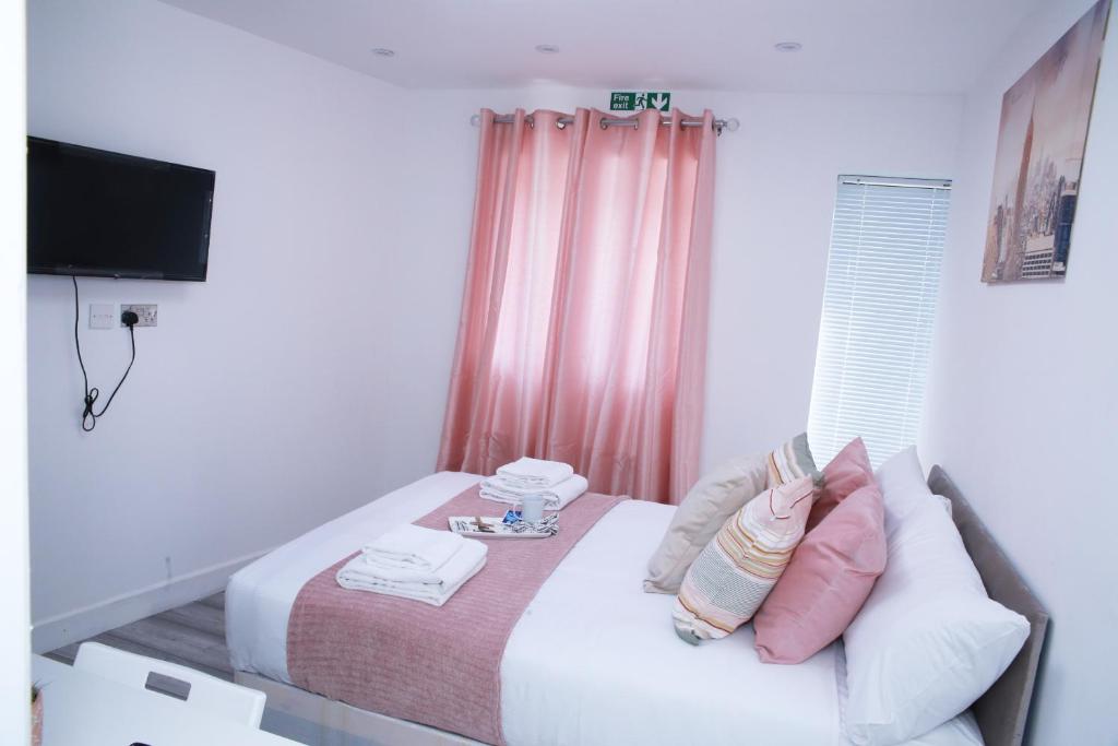 伦敦Harrow Luxury flat With free parking.的一间卧室配有一张带粉色窗帘的床和电视。