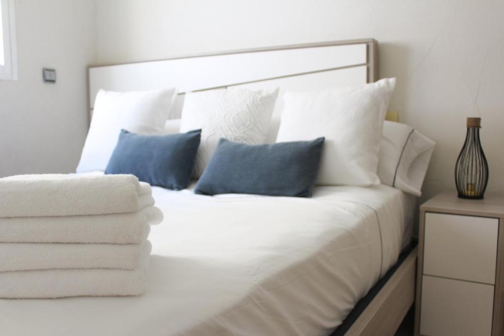圣波拉Apartamento Bahía的白色的床,配有白色床单和蓝色枕头