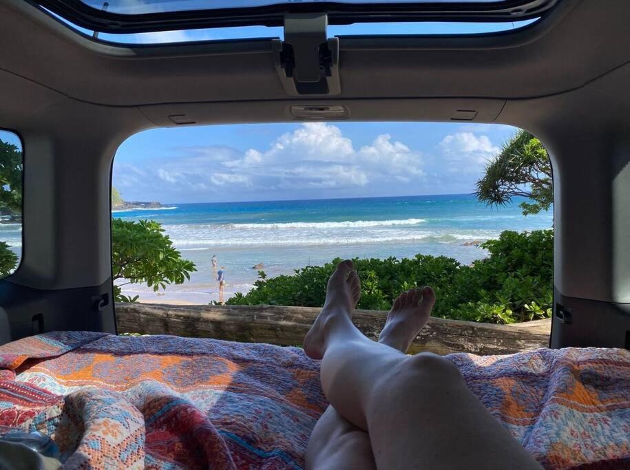 基黑Campervan/Maui hosted by Go Camp Maui的躺在床上,眺望着海滩的人