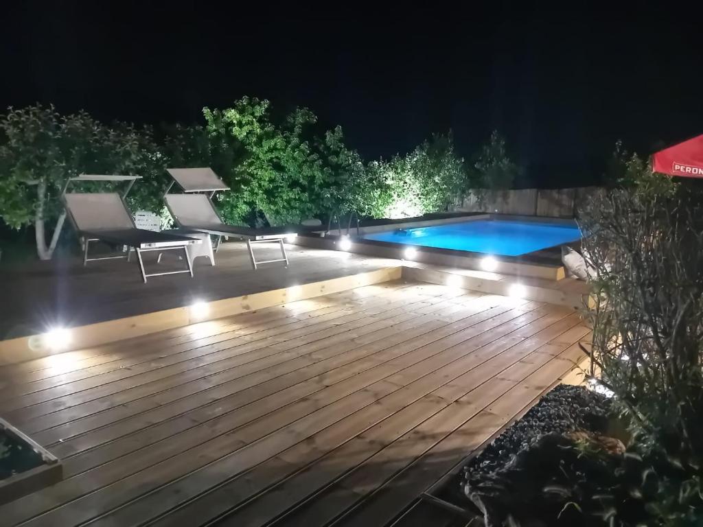 马丁纳弗兰卡Trullo Vito in Valle D itria con piscina的后院甲板,晚上设有游泳池