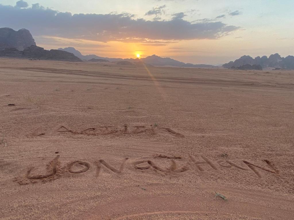 DisahEnjoy Wadi Rum stars的沙漠中的刻记,背景是日落
