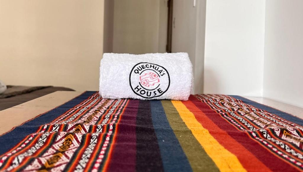马丘比丘QUECHUA´S HOUSE Hostal & Coffee的一条毛巾,放在五颜六色的地毯上