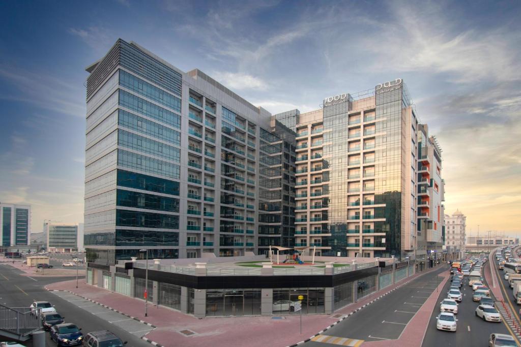 迪拜Jood Hotel Apartments的一座大型建筑,有汽车停在城市里