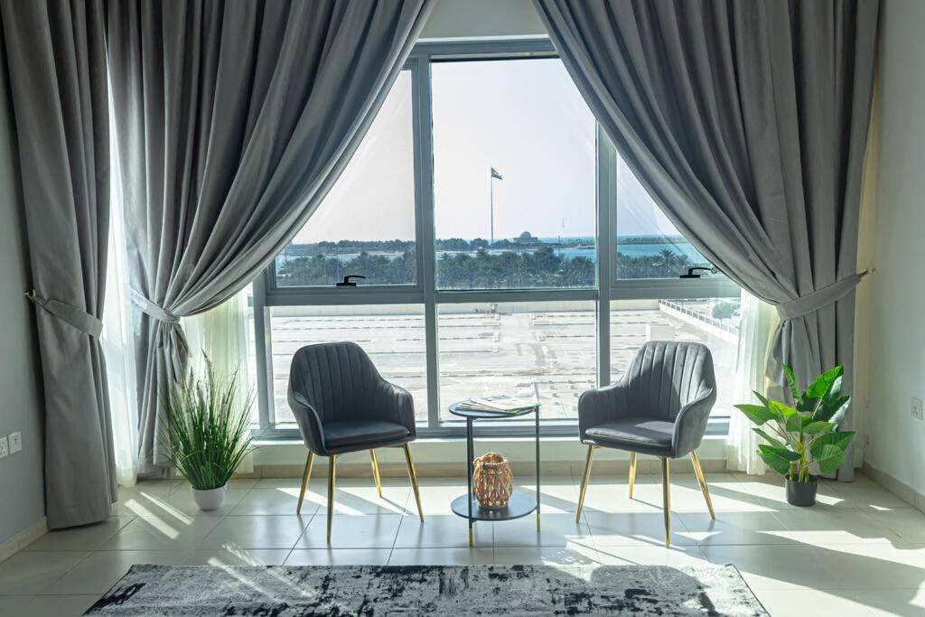 阿布扎比Super 2 Bedroom Sea View的大窗户前的两把椅子和一张桌子