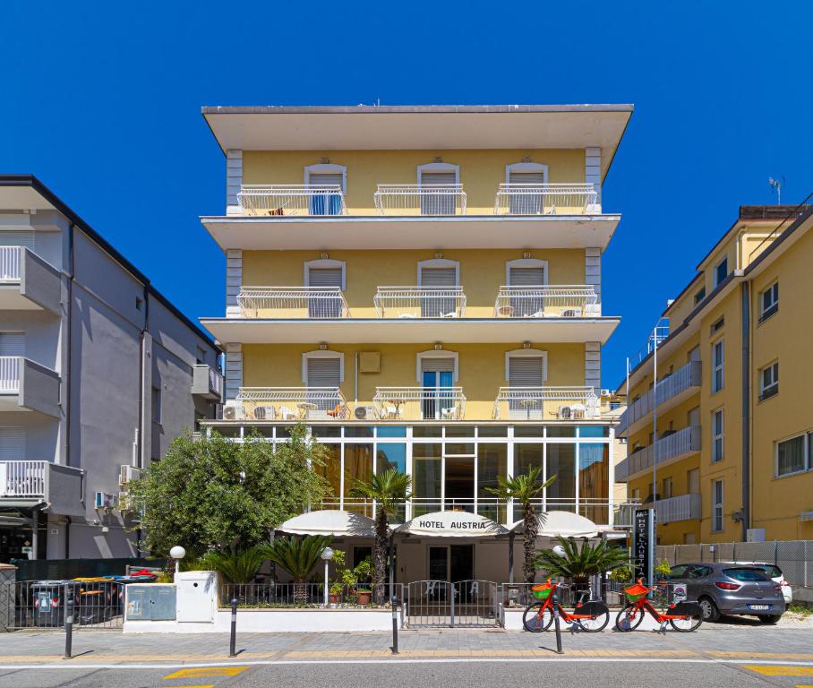 里米尼奥地利酒店的一座黄色的建筑,前面有自行车停放