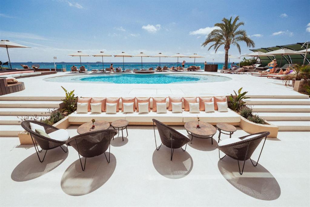 普拉亚登博萨AMA Ibiza的一个带游泳池和桌椅的度假酒店