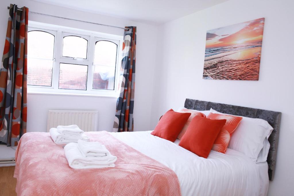 哈罗Kenton Cozy Apartment的一间卧室配有红色和白色枕头的床