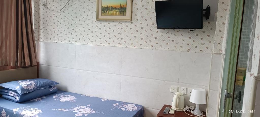 香港The Cultural Crashpad - 康乃馨旅館的卧室配有一张床,墙上配有电视。