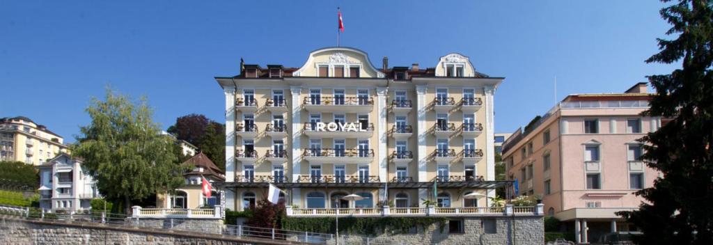 卢塞恩Hotel Royal Luzern的一座白色的大建筑,上面有旗帜