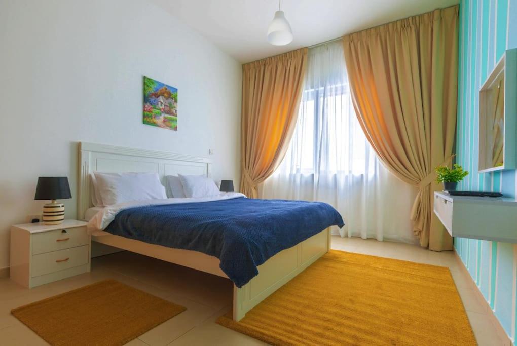 阿布扎比SPACIOUS 3 Bedroom Apartm Beach Front (Side View)的一间卧室配有一张带蓝色床单的床和一扇窗户。