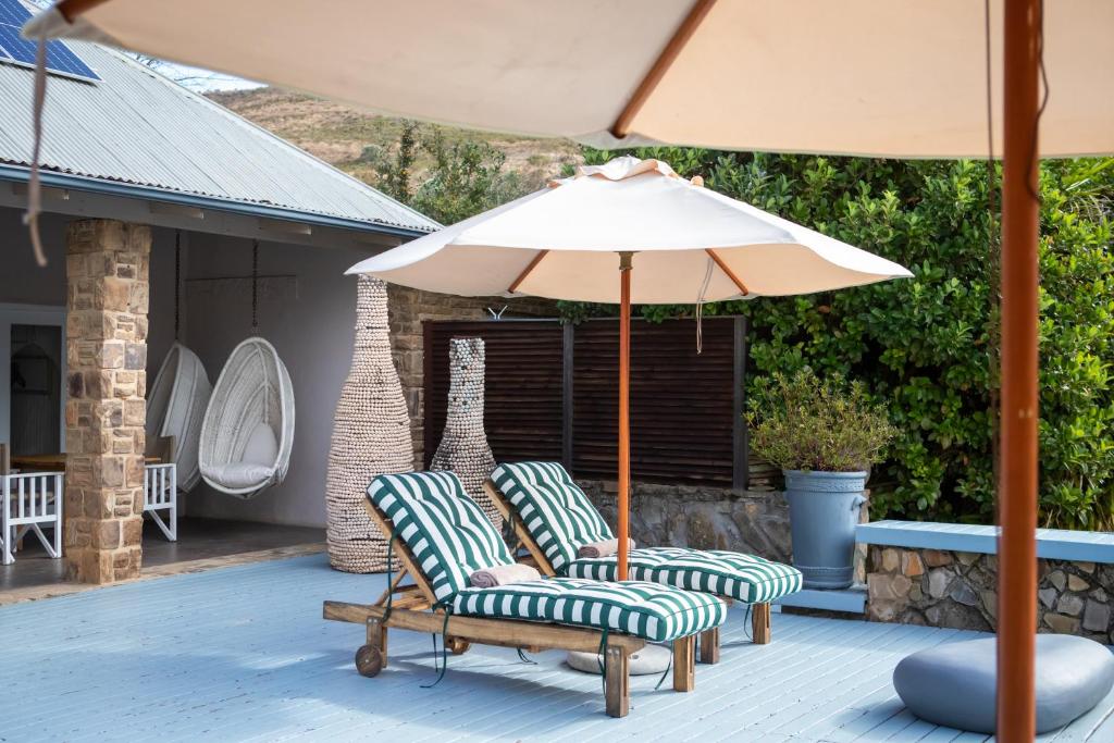 Rev EstatesQambathi Mountain Lodge的天井上配有两把椅子和一把遮阳伞