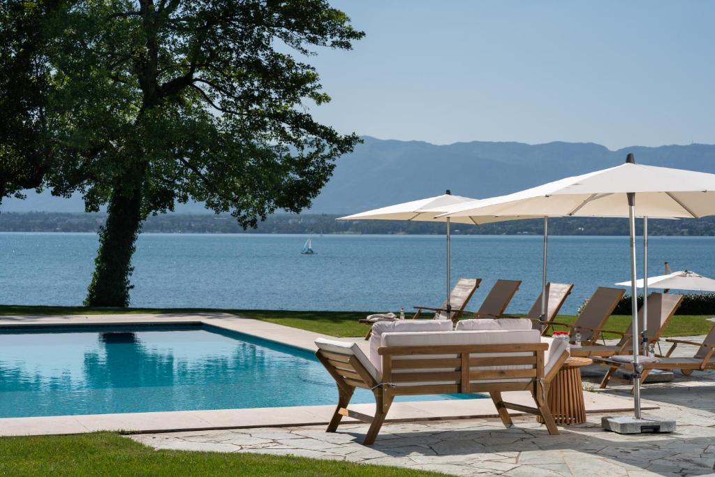 日内瓦Park Villa Geneva - Swiss Hotel Apartments的游泳池旁配有遮阳伞的桌椅