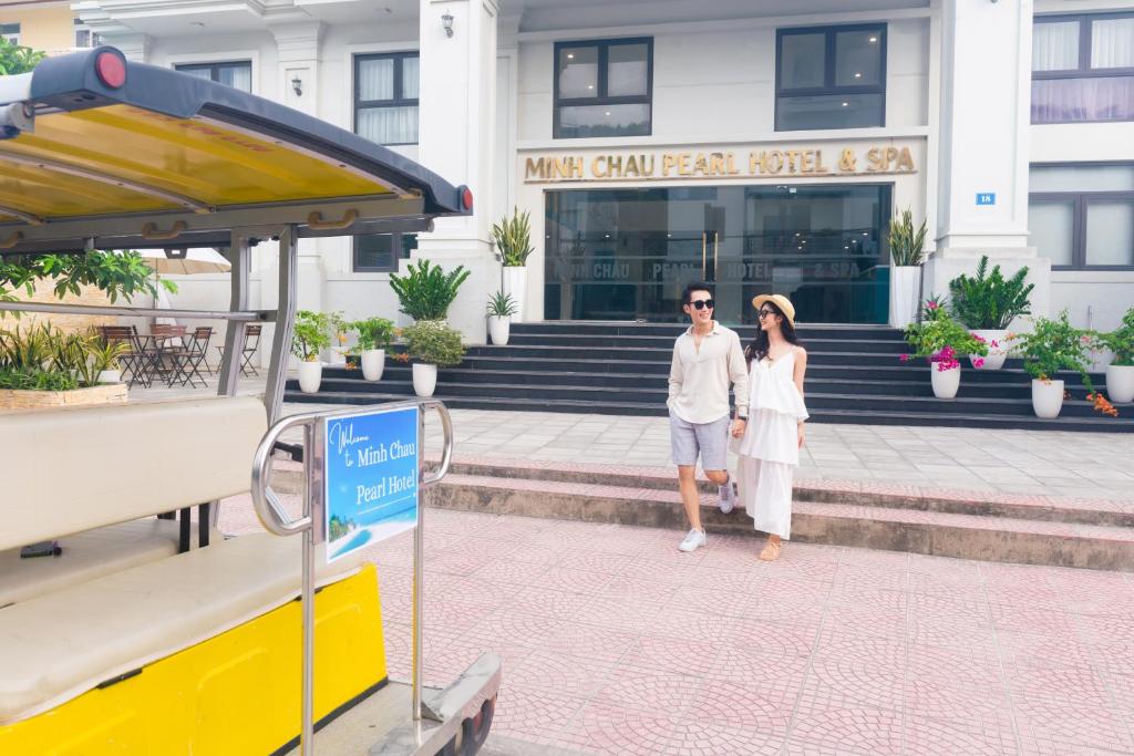 广宁Minh Chau Pearl Hotel & Spa - Quan Lan Island的站在建筑物前的男女
