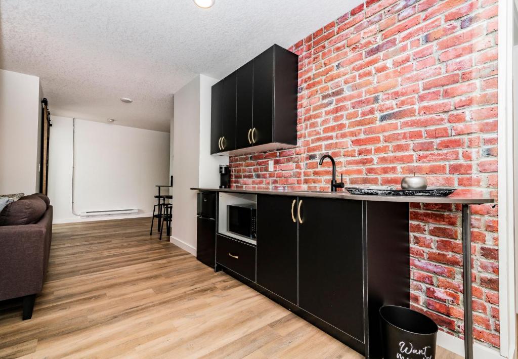ClairmontRNDup Urban Lofts的厨房设有砖墙和黑色橱柜