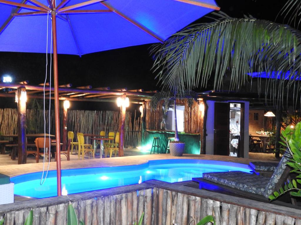巴拉格兰德Pousada Santa Aldeia的一个带遮阳伞和桌椅的游泳池