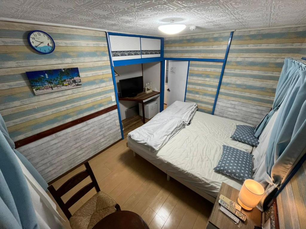Arazato宮古島ゲストハウス　マウイ的一间小卧室,配有一张床和墙上的时钟