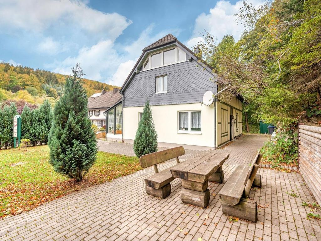 布里隆Deluxe Holiday Home in Brilon Wald near Ski Area的坐在房子前面的木凳