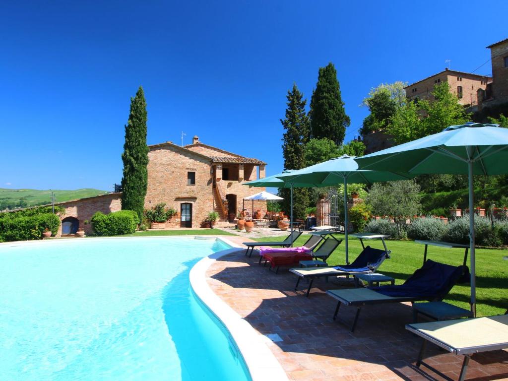 圣焦万尼达索Attractive Farmhouse in Montalcino with Terrace的一个带草坪椅和遮阳伞的游泳池