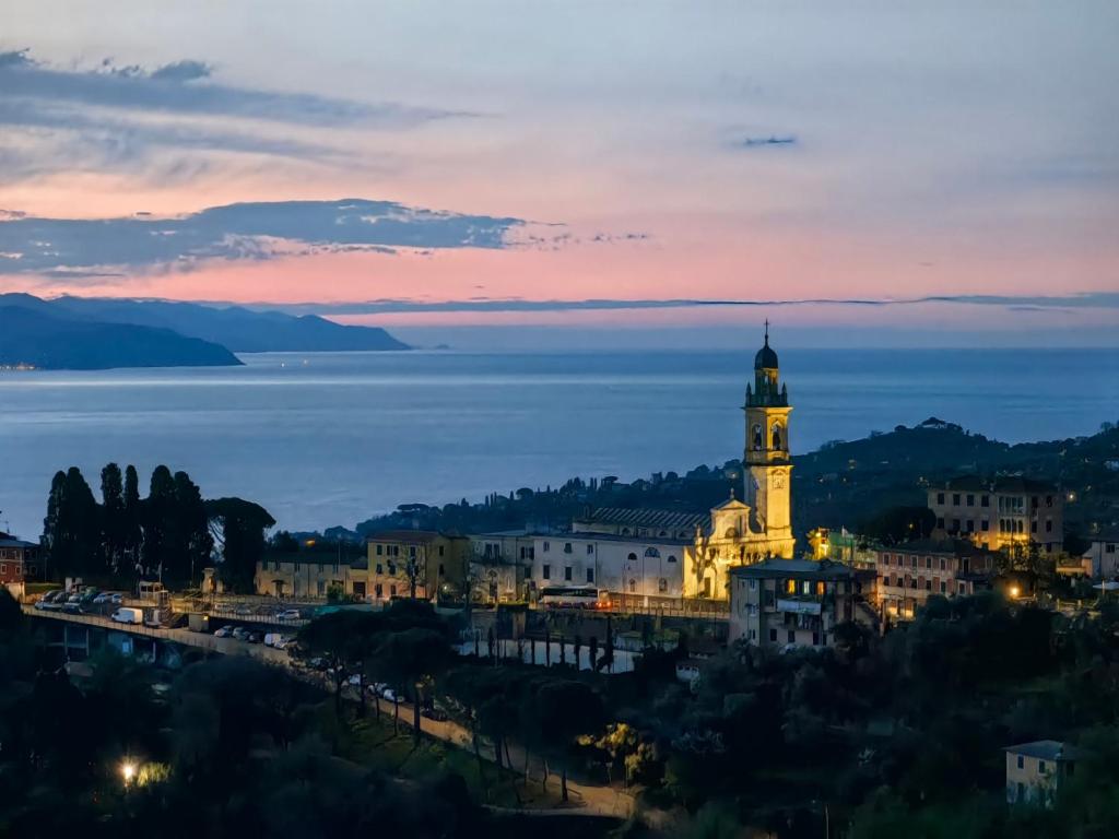 圣玛格丽塔-利古雷La Mansarda di San Lorenzo的享有城市美景,晚上设有钟楼