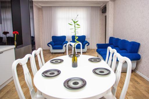 苏姆盖特VIP апартамент的一间配备有白色桌子和蓝色椅子的用餐室