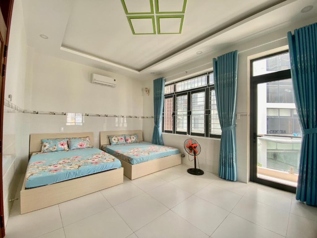 芽庄Homes Stay 19 Phạm Ngọc Thạch的一间卧室设有两张床和蓝色窗帘