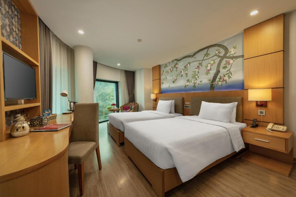 河内HALO HANOI HOTEL的酒店客房设有两张床、一张桌子和一台电视。