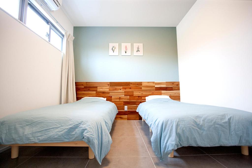 名户Hichu House ハイチューハウス的一间卧室设有两张床和窗户。
