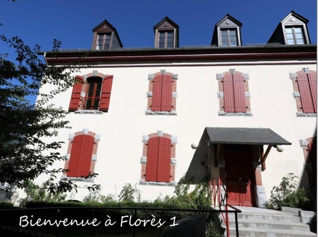 吕兹-圣索沃尔Le Florès Idéalement situé Centre Luz Appart T3 6 personnes Parking的白色的建筑,有红色的门窗