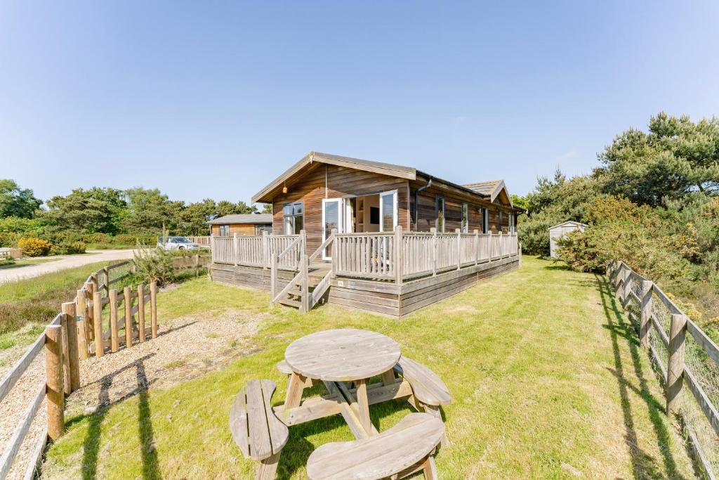 KellingHeathland Lodge - Norfolk Cottage Agency的小木屋设有桌子和围栏