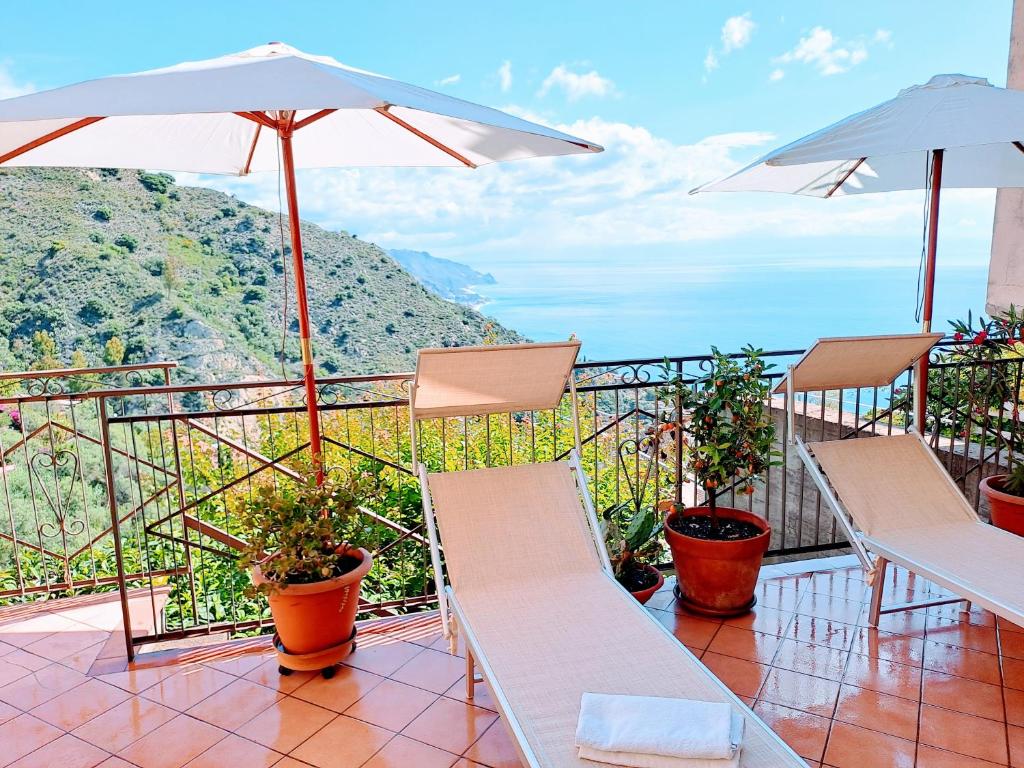陶尔米纳Castel Tauro Apartment的阳台配有椅子和遮阳伞,享有风景。