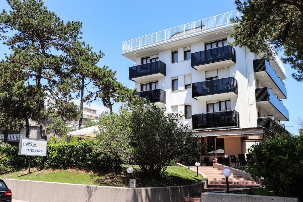 利尼亚诺萨比亚多罗伊甸酒店的带阳台和树木的白色公寓大楼