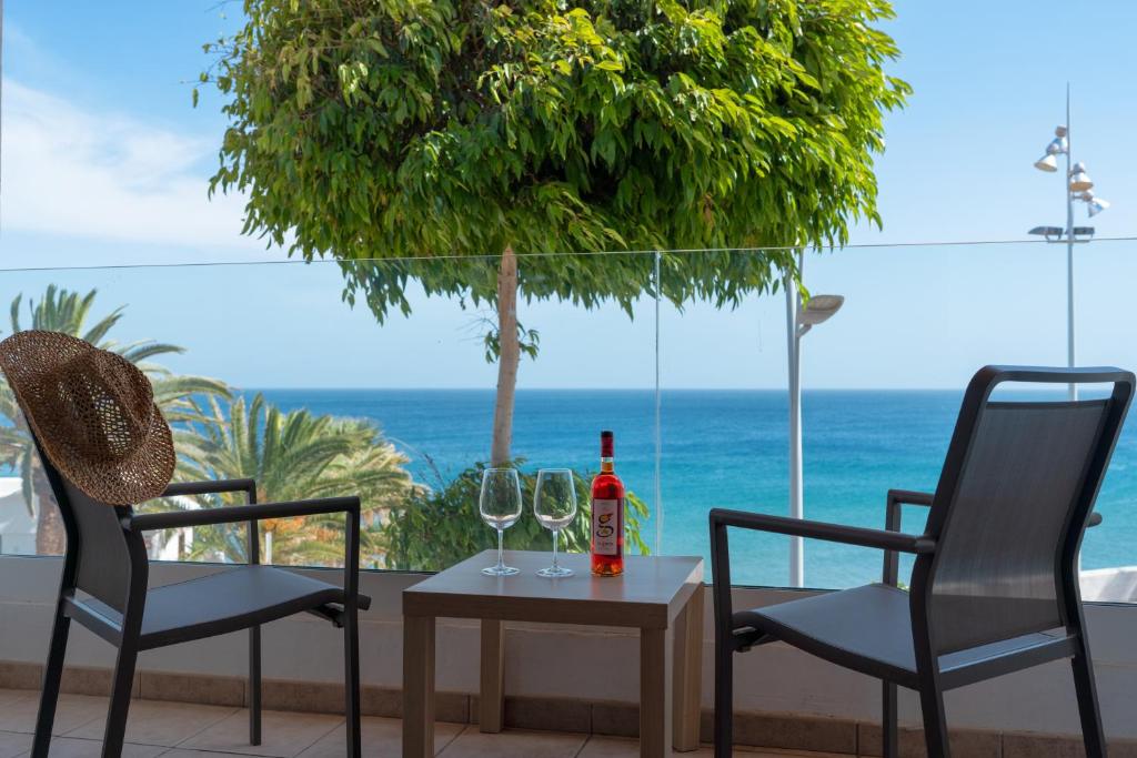 卡门港Sabbia Suites Sea View La Playita的一张桌子、两把椅子和一瓶葡萄酒