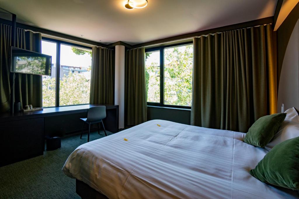 亨克格林酒店的卧室配有一张床、一张书桌和窗户。