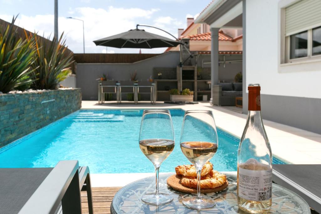 奥比多斯Óbidos Pool & Charm的游泳池畔的桌子上放两杯葡萄酒