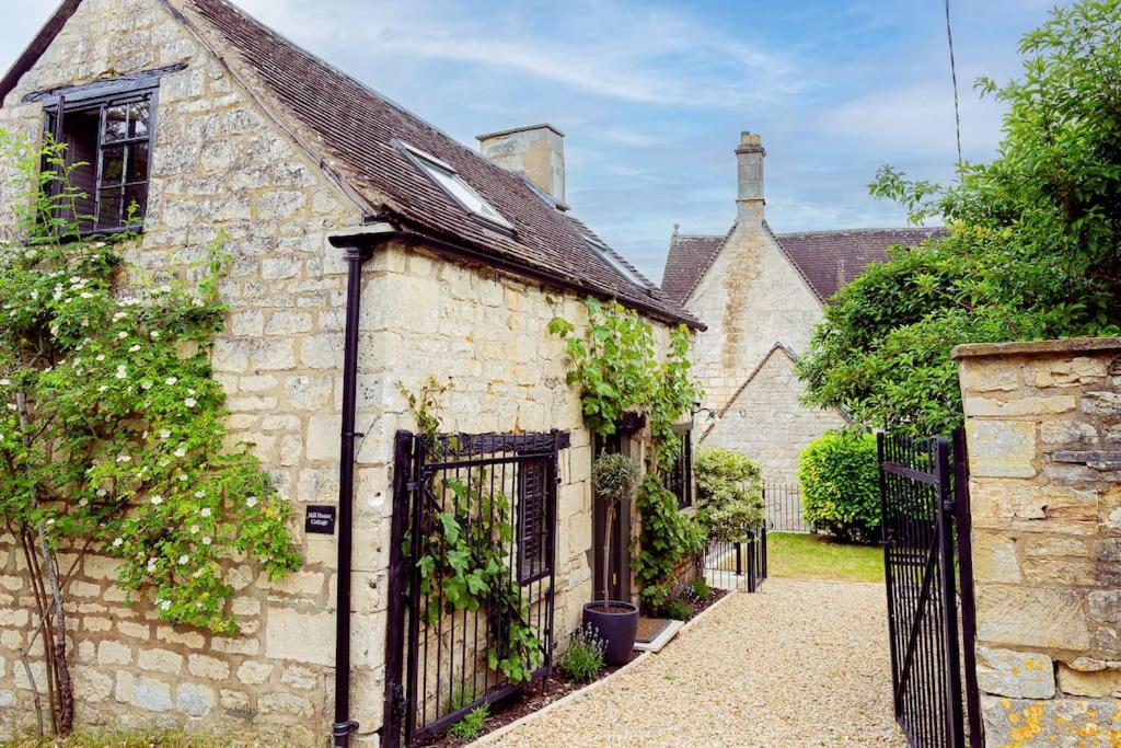 HarescombeMill House Cottage - Star Stay on The Cotswold Way的一座带黑色门的老石屋