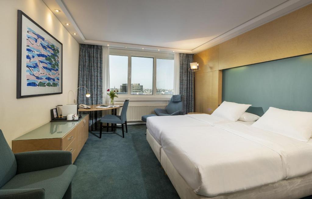柏林玛丽蒂姆柏林普洛艾特酒店的酒店客房设有一张大床和一张书桌。