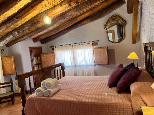 Villar del ArzobispoCasa rural La Boticaria的一间卧室配有带毛巾和镜子的床