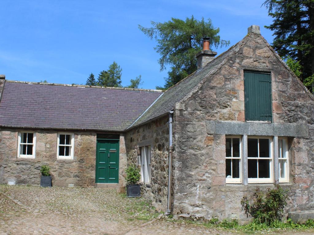 AlfordSteading Cottage - Craigievar Castle的古老的石头小屋,设有绿门和窗户