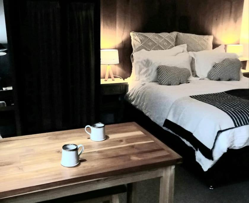 奇切斯特The Old Barn Annexe, cosy stay near the city, beach, South Downs & Goodwood的一间卧室配有一张床和一张桌子,上面有两张杯子