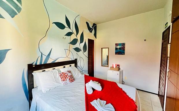 卡姆布库Pousada Sunrise Beach的一间卧室配有一张床铺,床上铺有红色毯子