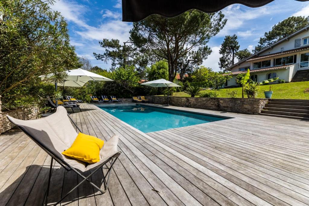 比达尔SERENITY - KEYWEEK Bidart swimming pool villa的一个带椅子的甲板和一个游泳池