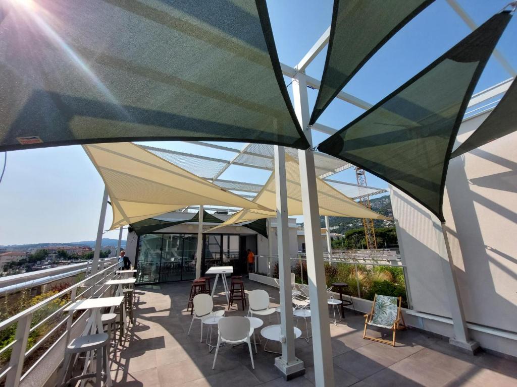 土伦Apparthotel Le Hüb TOULON的屋顶庭院配有桌椅和遮阳伞
