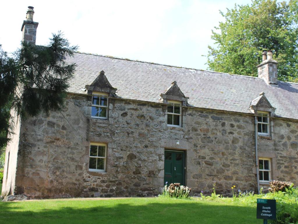 AlfordSouth Mains Cottage - Craigievar Castle的一座古老的石头建筑,设有绿门