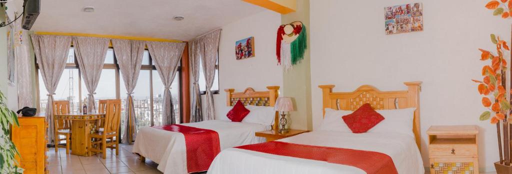 HuejotzingoHotel Carnaval的一间卧室配有两张带红色枕头的床